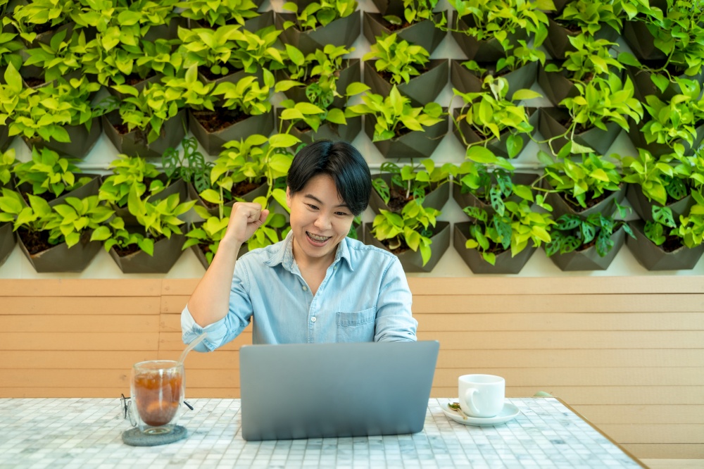 Smiling man looking at laptop screen,Checking finances,Sitting at table at home.