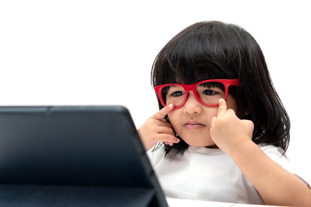 Little Asian Preschooler girl wearing red glasses and using tablet pc on white background, Asian girl talking and learning with a video call with a tablet, Educational concept for school kids.