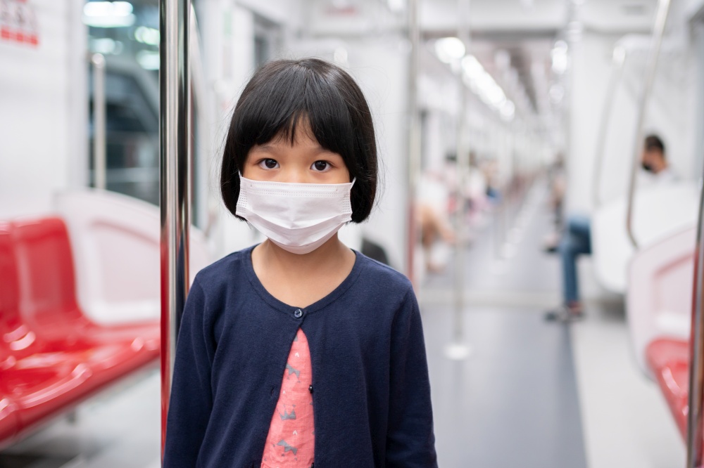 Little girl with surgical mask face protection flu and Virus outbreak in public transportation (skytrain or subway). Concept of New normal lifestyle, Using public transport to travel to school.