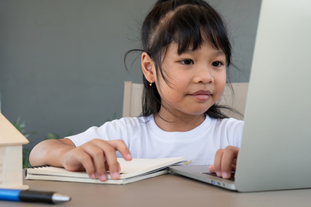 Asian girl student using the laptop for online learning class and doing homework at home, Education and distance learning for children Homeschooling concept