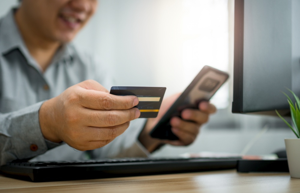 A Man holding credit card and using smartphone for payment online for purchase after order products via the internet. The concept of technology for e-commerce (electronic commerce)