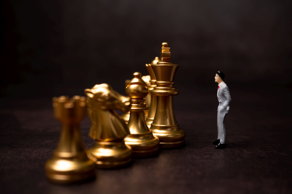 Figures businessman standing in front of the golden chess on black isolated background. Concept of business analysis and strategy. Stepping into the startup, new business player