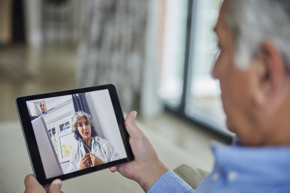 Man Having Remote Consultation With Doctor At Home Using Digital Tablet