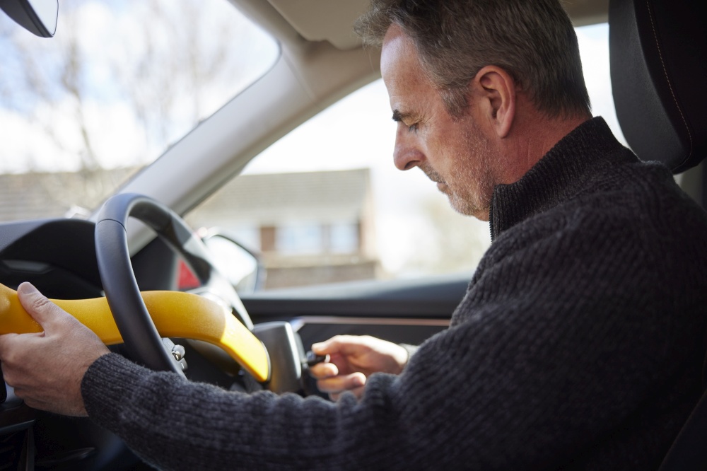 Mature Man Fitting Manual Steering Wheel Lock In Car