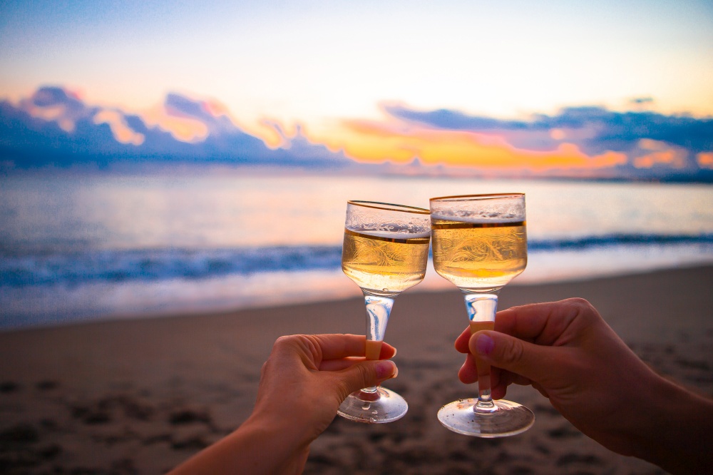 Two glasses of white wine on the beach at sunset. two glasses on the white sandy beach