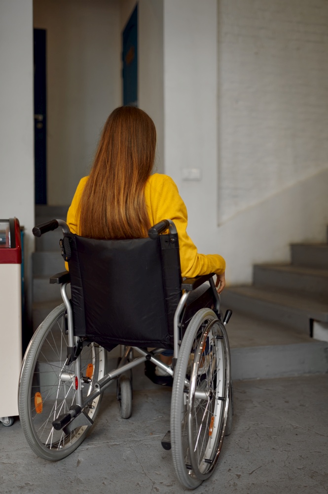 Disabled female student in wheelchair at the stairs, disability problems, university interior on background. Handicapped woman studying in college, paralyzed people get knowledge. Disabled female student in wheelchair at stairs