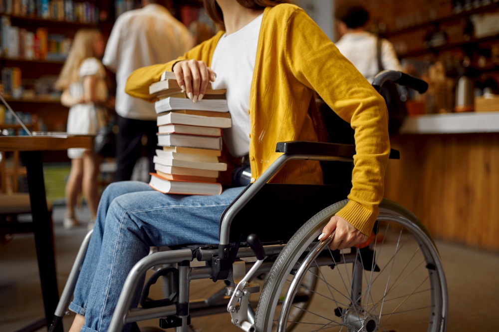 Disabled female student in wheelchair holds stack of books, disability, university library interior on background. Handicapped woman studying in college, paralyzed people get knowledge. Disabled female student holds stack of books