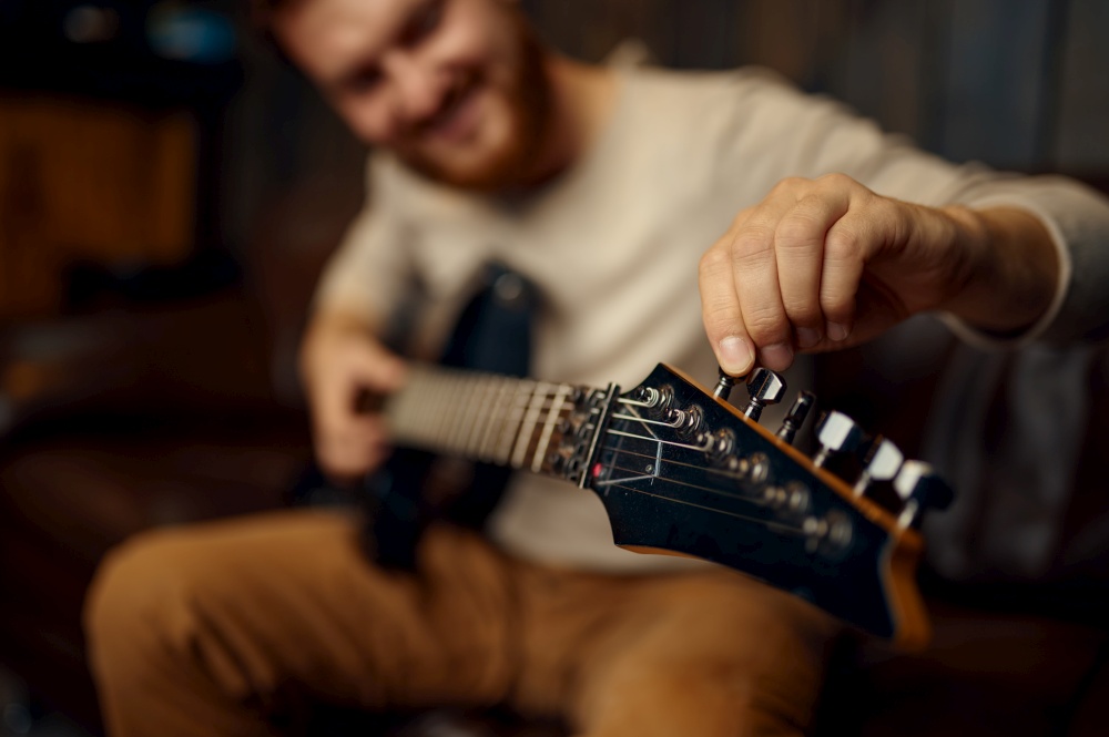 Young man guitarist tune guitar before playing. Music lesson creative hobby. Selective focus closeup. Young man guitarist tune guitar before playing