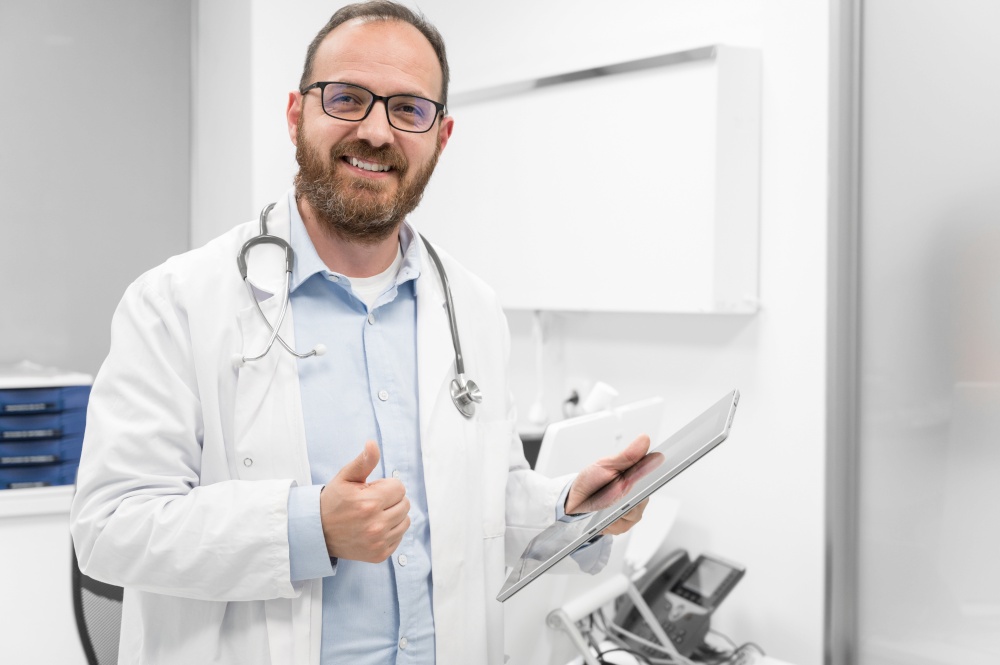 Friendly male doctor smiling and giving thumb up sign. High quality photo. Friendly male doctor smiling and giving thumb up sign
