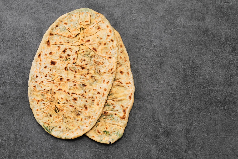 Gozleme, a traditional vegetarian dish of Turkish or Caucasian cuisine in the form of a flatbread stuffed with greens and cheese, wrapped inside. Baked in pan. Top view with copy space