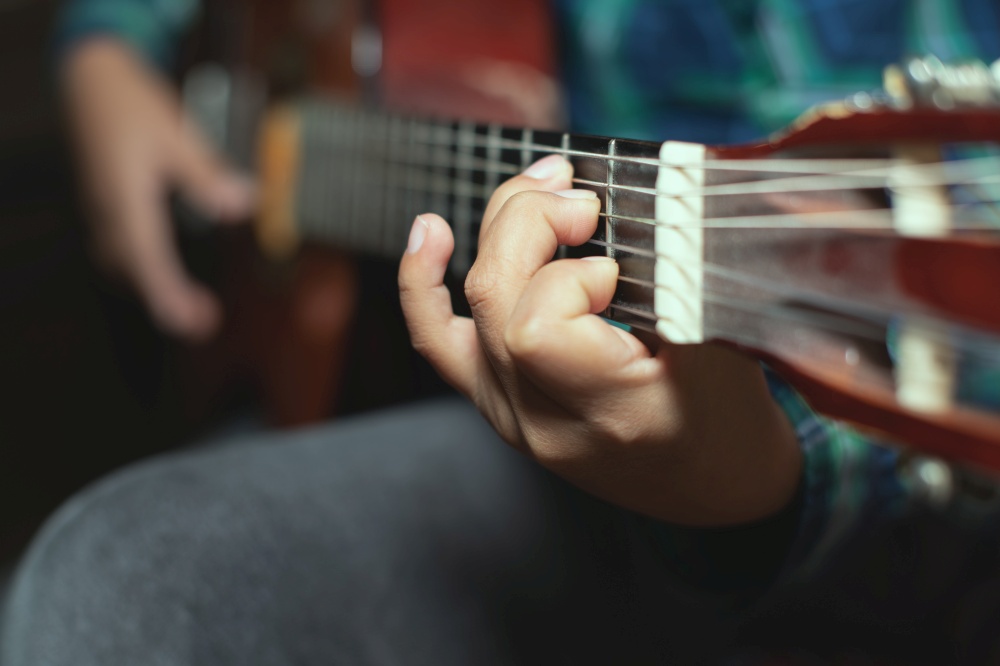 Left hand detail of a child with chord on classical guitar