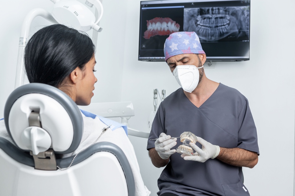 Dentist making a explanation to a patient while holding a plastic dental mould in a dental clinic. Dentist explaining to a patient how a dental mould works in a dental clinic