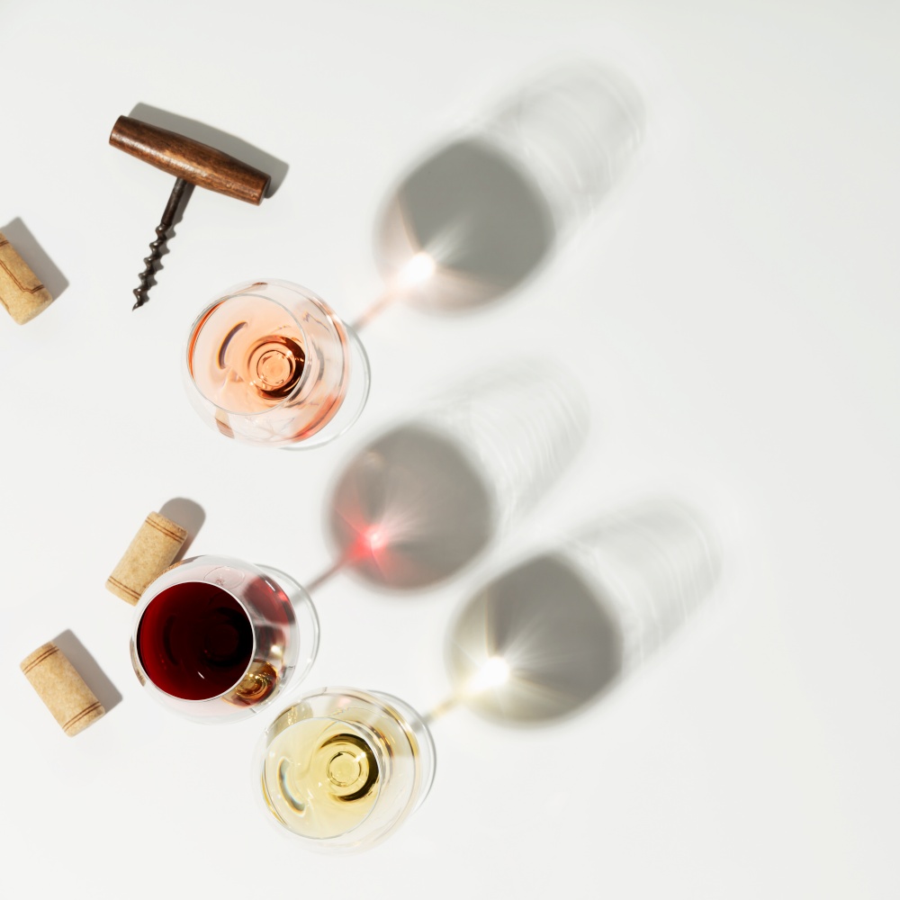 Wine composition with beautiful sunlight and shadows on white background. Top view, flat lay, square composition
