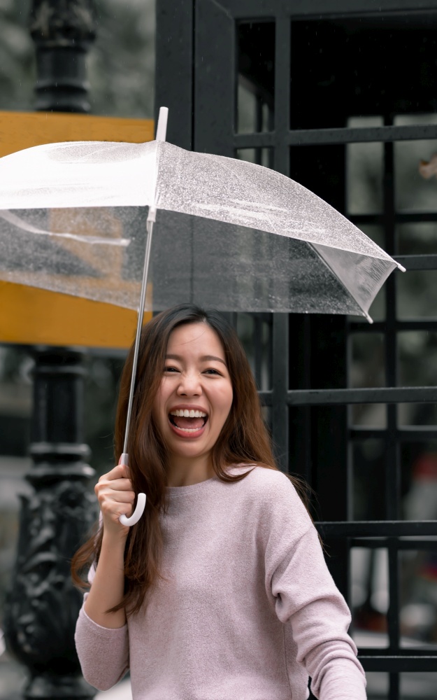 Asian beautiful woman holding umbrella in raining season while standing in city. Lifesyle Concept.