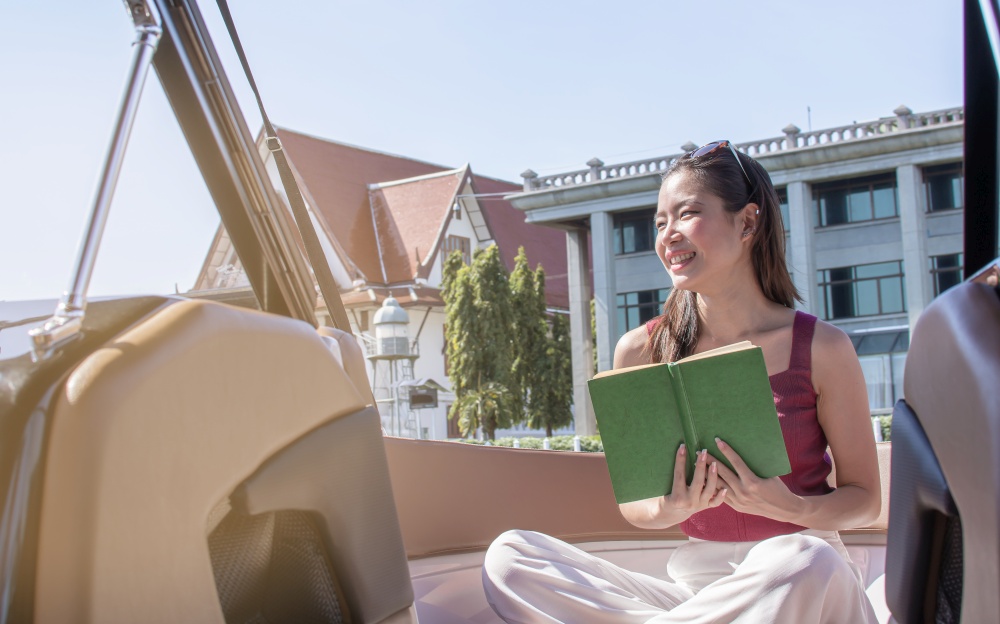 Asian beautiful woman reading book while traveling and sitting on boat with background of beautiful lanscape. Summer Travel and Lifestyle Concept.