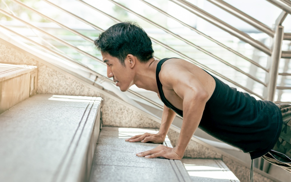 Asian handsome and healthy man doing exercise by pushing up stairs outdoor. Sport and Lifestyle Concept.