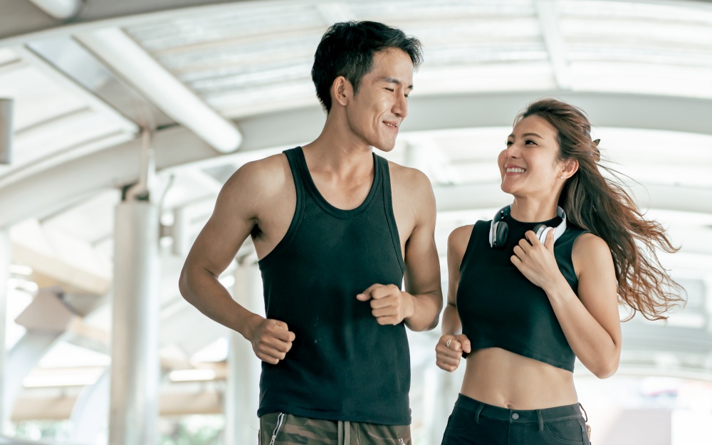 Asian Healthy and Sportive couple smiling to each other, running and jogging outdoor. Sport and Lifestyle Concept.