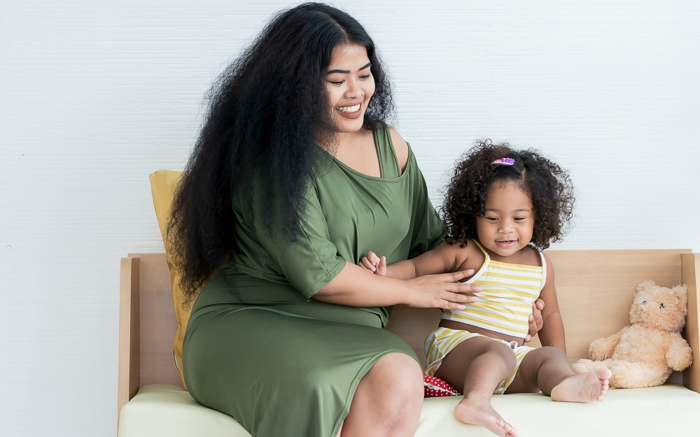 African black mother with afro hair playing with her little daughter in living room at home. Education and Family Concept.