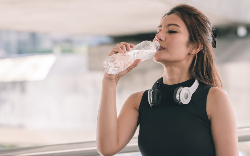 Portrait of Asian healthy and sportive woman wearing sport bra and drinking water. Sport and Lifestyle Concept.