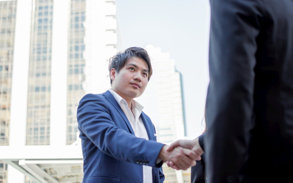 Asian young business man shaking his hand to make a successful deal or agreement