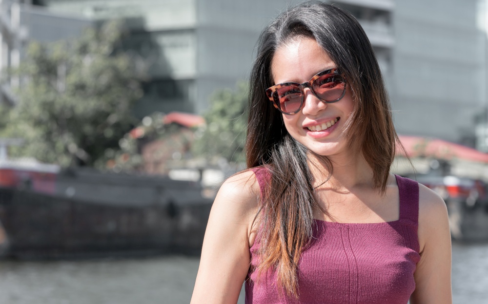 Portrait of asian beautiful woman wearing sunglasses and standing beside the river while travel on vacation. Summer Concept.
