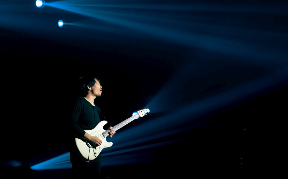 An asian guitarist showing his performance on stage with blue spot light. Entertainment and Concert Concept.