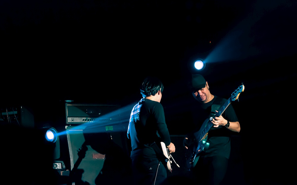 Two asian guitarists showing their performance on stage with blue spot light. Entertainment and Concert Concept.