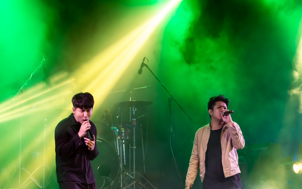 Two asian singers showing their performance on stage with colorful spot light. Concert and Entertainment Concept.