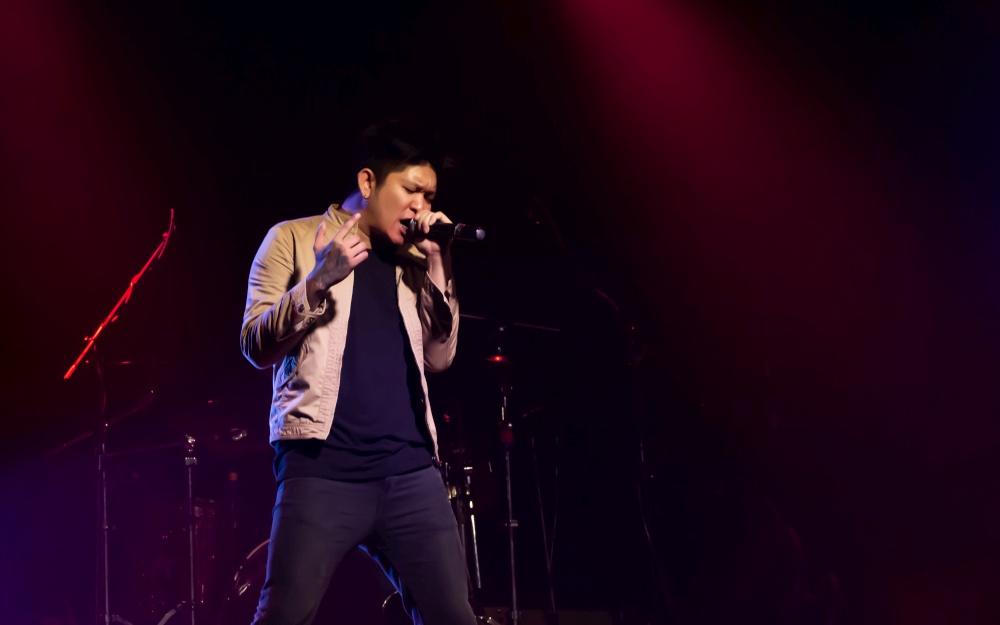 An asian male singer showing his porformance on stage. Entertainment and Concert Concept.