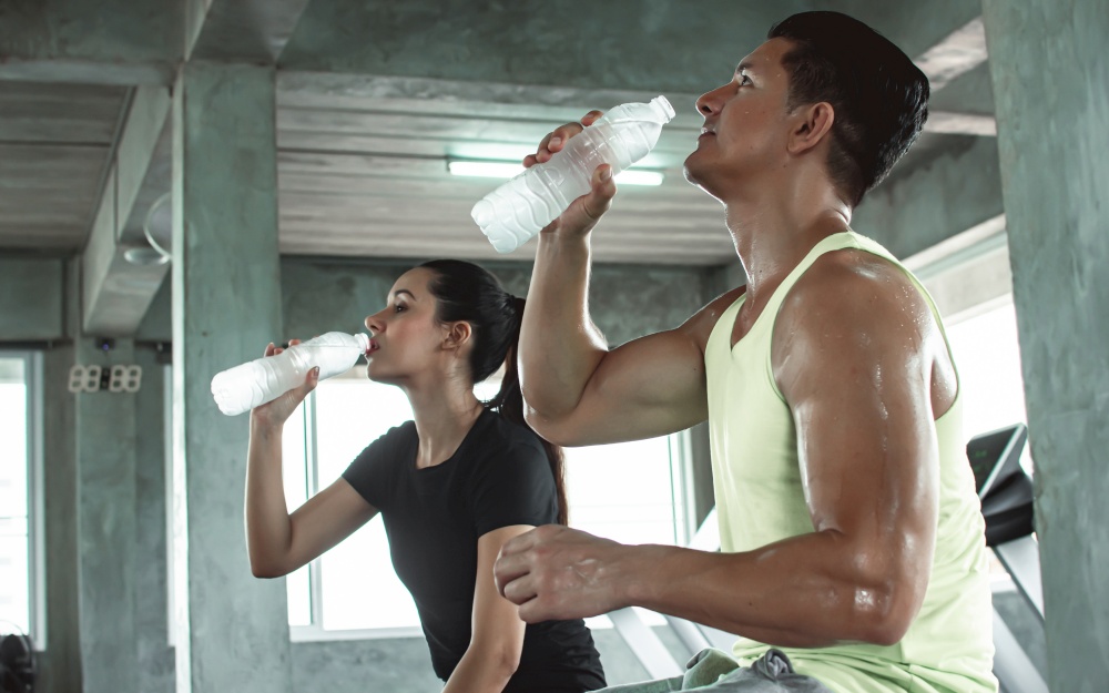 Caucasian man and woman are drinking water after doing exercise. Sport and Healthy Concept.