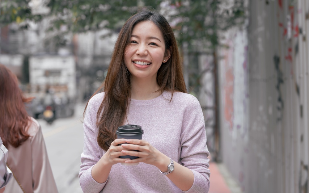 Asian beautiful woman drinking coffee while walking beside the street in winter season. Lifestyle Concept.