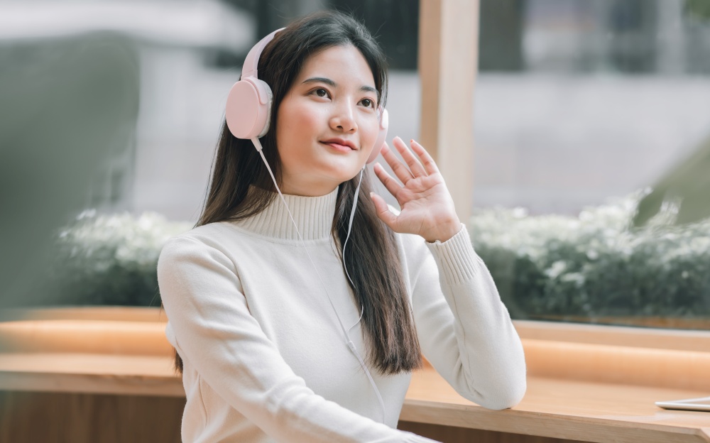 Asian beautiful woman wearing headphone to listen music in winter season. Lifestyle and Leisure Concept.