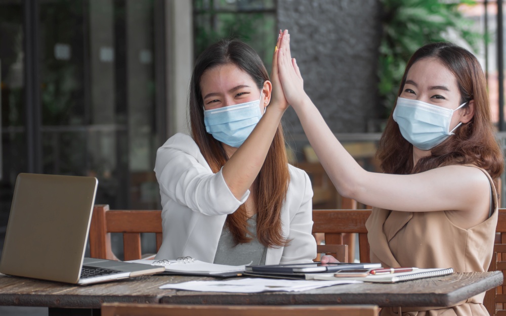 Two asian business woman wearing mask and being happy after getting success on their job
