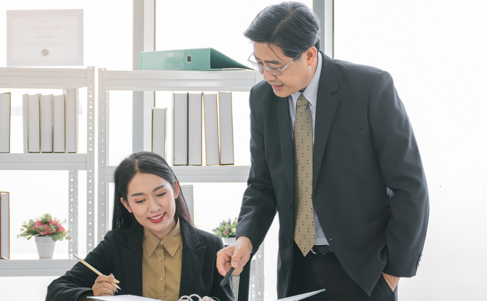 An asian senior executive male boss coaching and training his secretary about jobs and plans in indoor office. Business Concept.