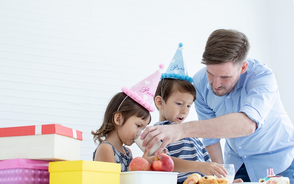 Caucasian father celebrating his children&rsquo;s birthday while little boy and girl are very happy. Party and family concept.