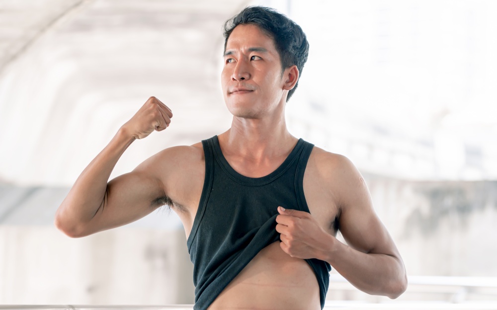 Asian sportive man showing his shape after doing exercise outdoor