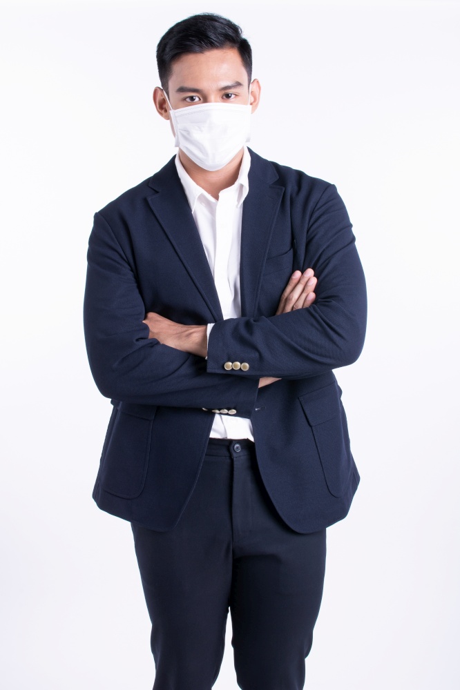 Asian young business man wearing formal suit and mask to protect virus while standing on white background with copy space. Working and Medical Concept.