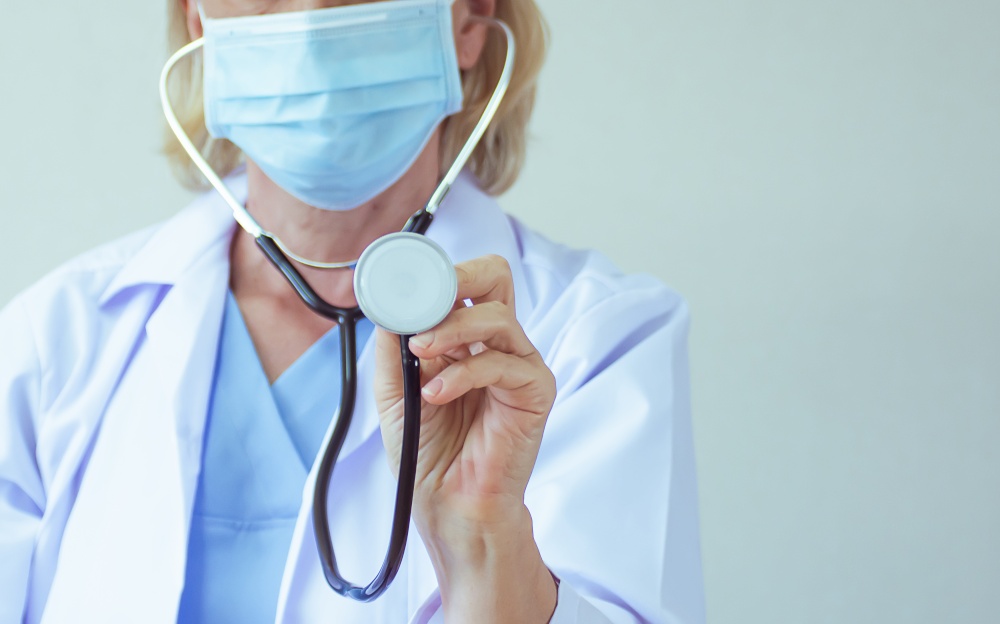 Selective focus on stethoscope with blur background of female doctor wearing mask. Health and Medical Concept.