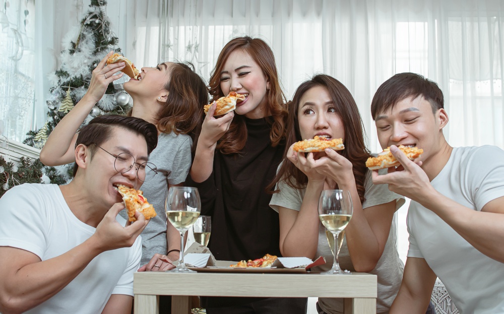 Group of asian people joining party at home, talking and eating pizza together. Lifestyle Concept.
