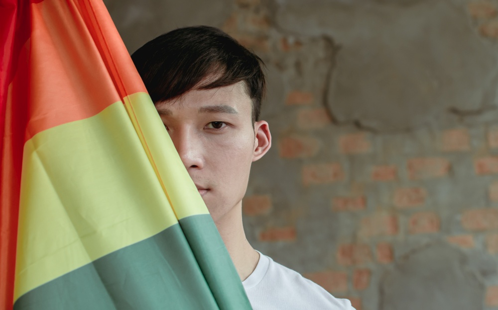 Portrait of Asian handsome man holding rainbow flag showing about LBGT concept.
