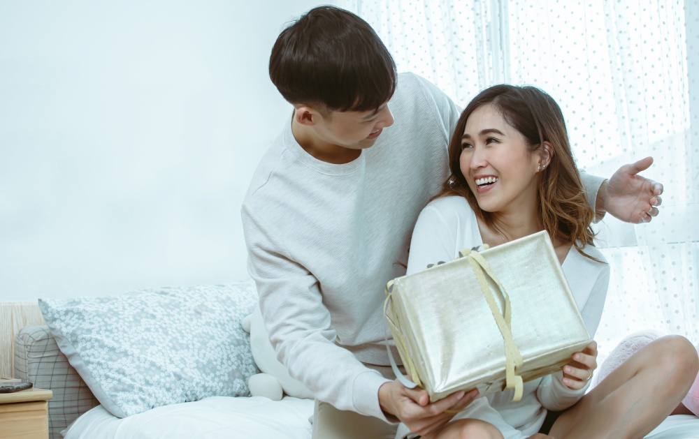 Asian handsome man making surprise and give a gift box to his girlfriend on valentine&rsquo;s day or birthday. Lifestyle Concept.