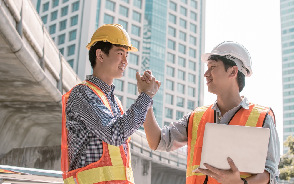 Two asian male engineers shaking their hands after finishing and being success on their construction project
