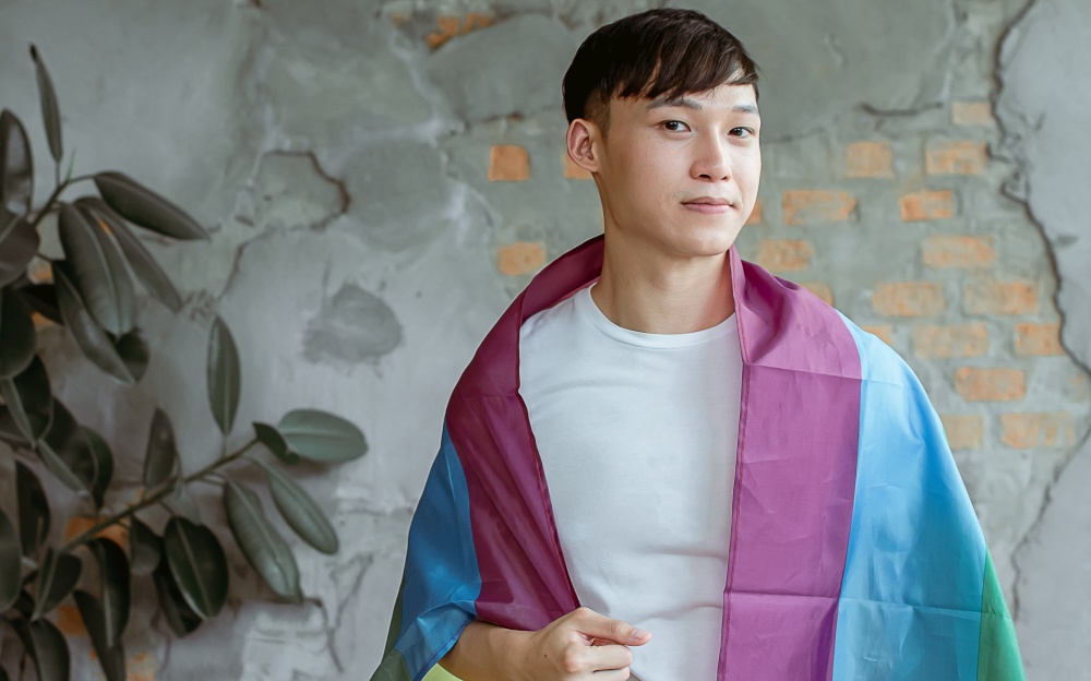 Asian handsome man wearing white shirt and rainbow flag. Lifestyle and LGBT Concept.