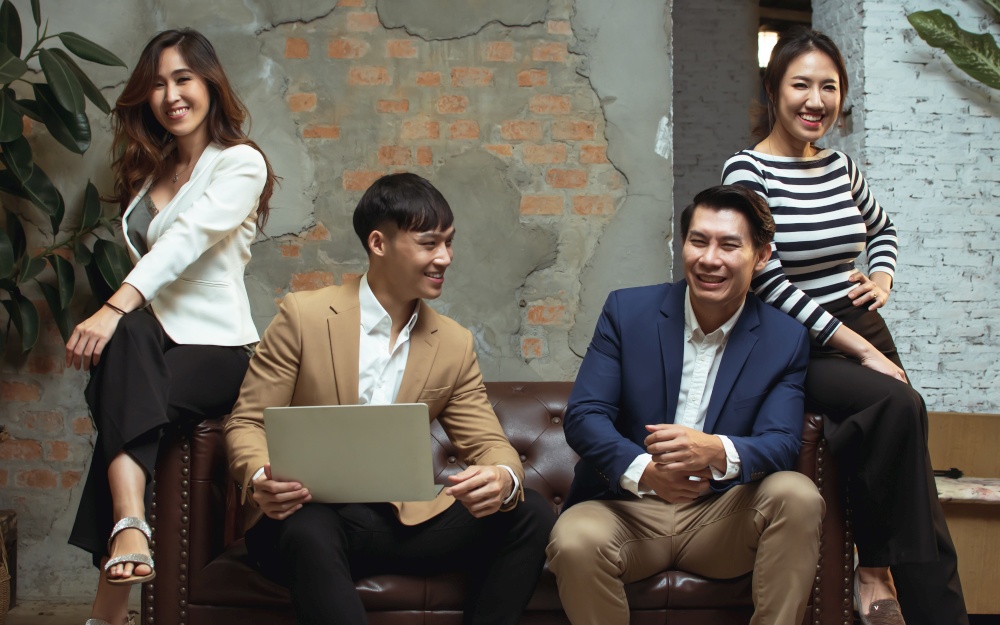 Portrait of a group of businesspeople wearing formal suit, smiling and holding laptop in workplace