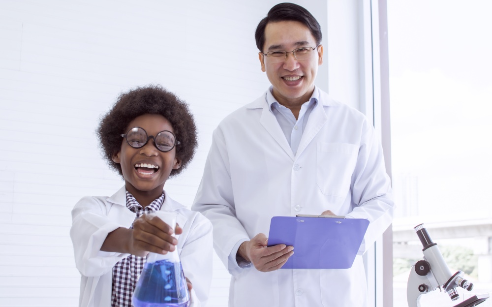 Asian male teacher is teaching science and experiment to African black boy in classroom at school. Education Concept.