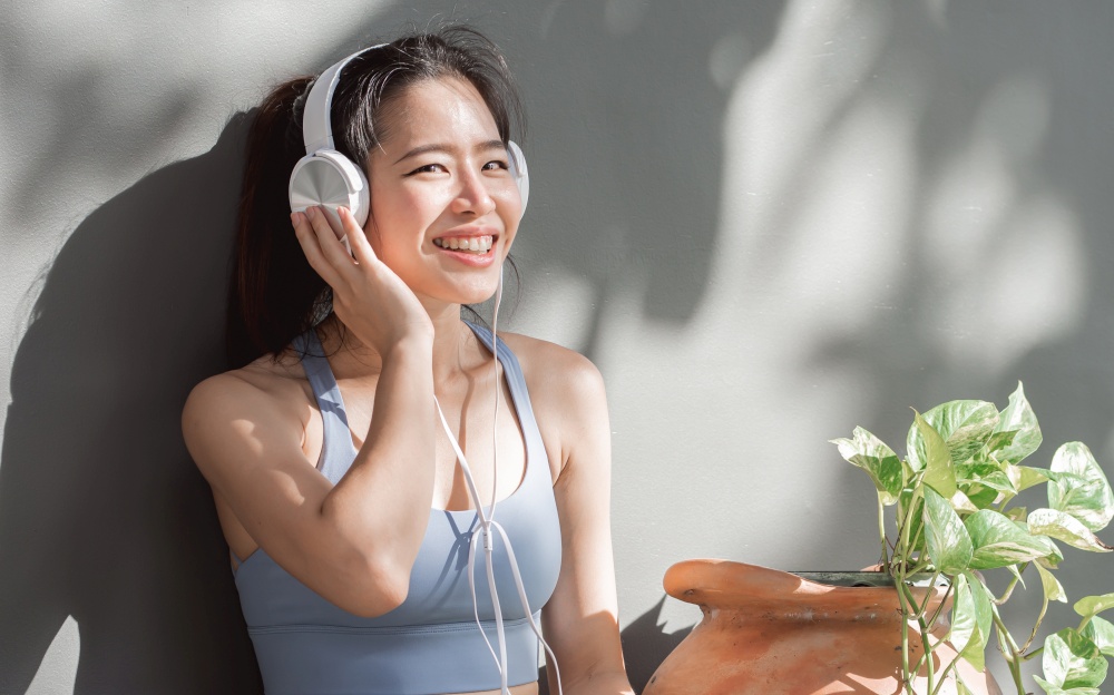 Portrait of asian healthy and sportive woman wearing sport bra and listen music at cozy home.