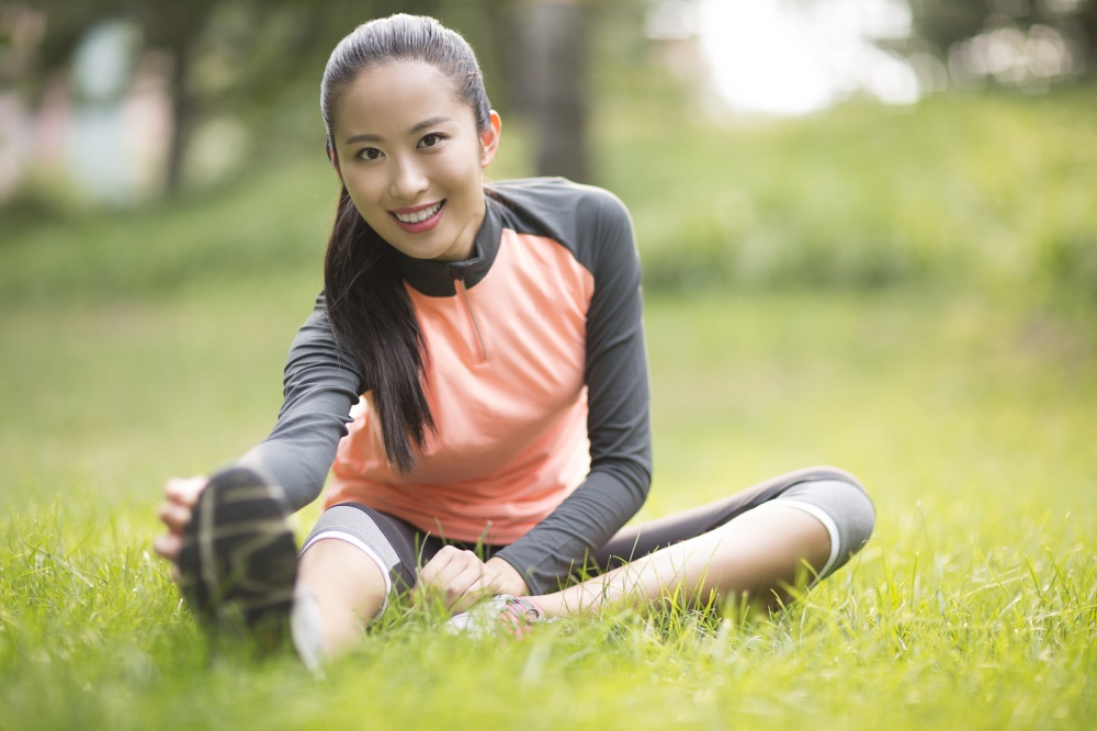 Energetic young woman exercising on the lawn