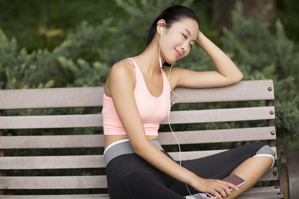 Woman in tracksuit listening to music on her phone
