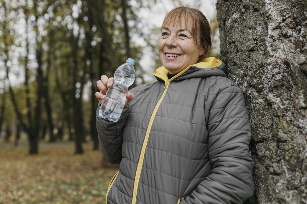 senior woman drinking water after working out nature
