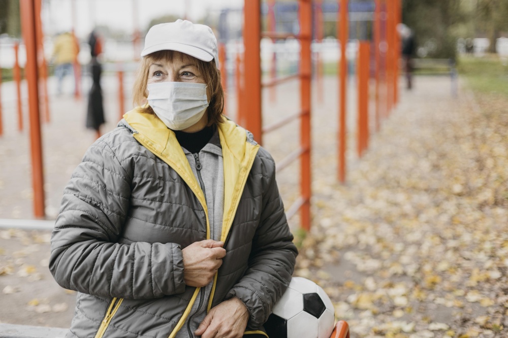 senior woman with medical mask football outdoors